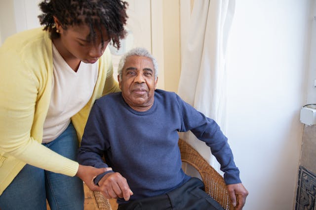 a young woman assisting an old man A young woman assisting her elder in sitting down